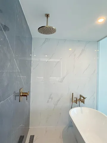 a view of an empty room with kitchen view and wooden floor