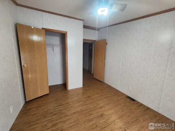 a view of an empty room with wooden floor and a closet