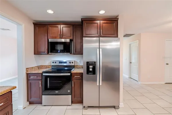 a kitchen with stainless steel appliances granite countertop a refrigerator a stove and a sink