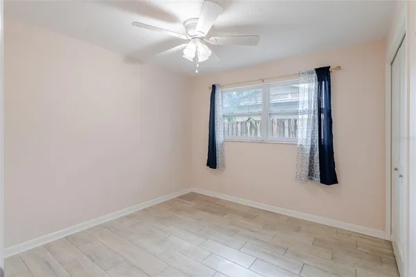 an empty room with windows and fan