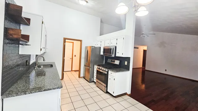 a kitchen with stainless steel appliances granite countertop a sink a stove and a refrigerator