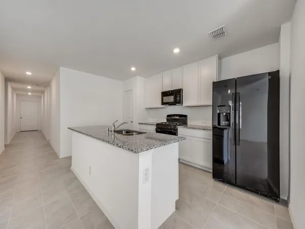 a kitchen with granite countertop a refrigerator and a stove top oven