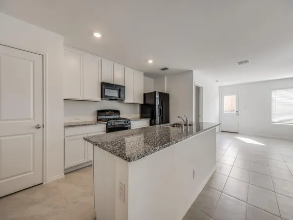 a kitchen with stainless steel appliances granite countertop a stove a sink and a microwave