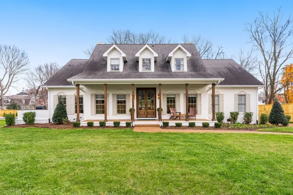 a front view of a house with a garden and trees