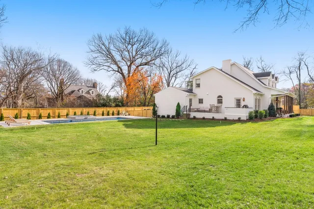 a view of a white house with a big yard and large trees