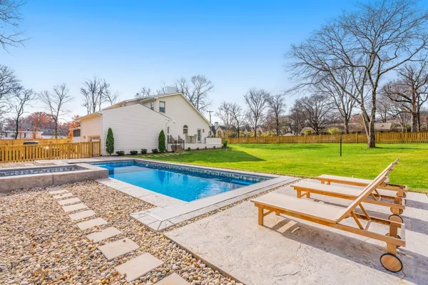 a view of swimming pool with lawn chairs and a big yard