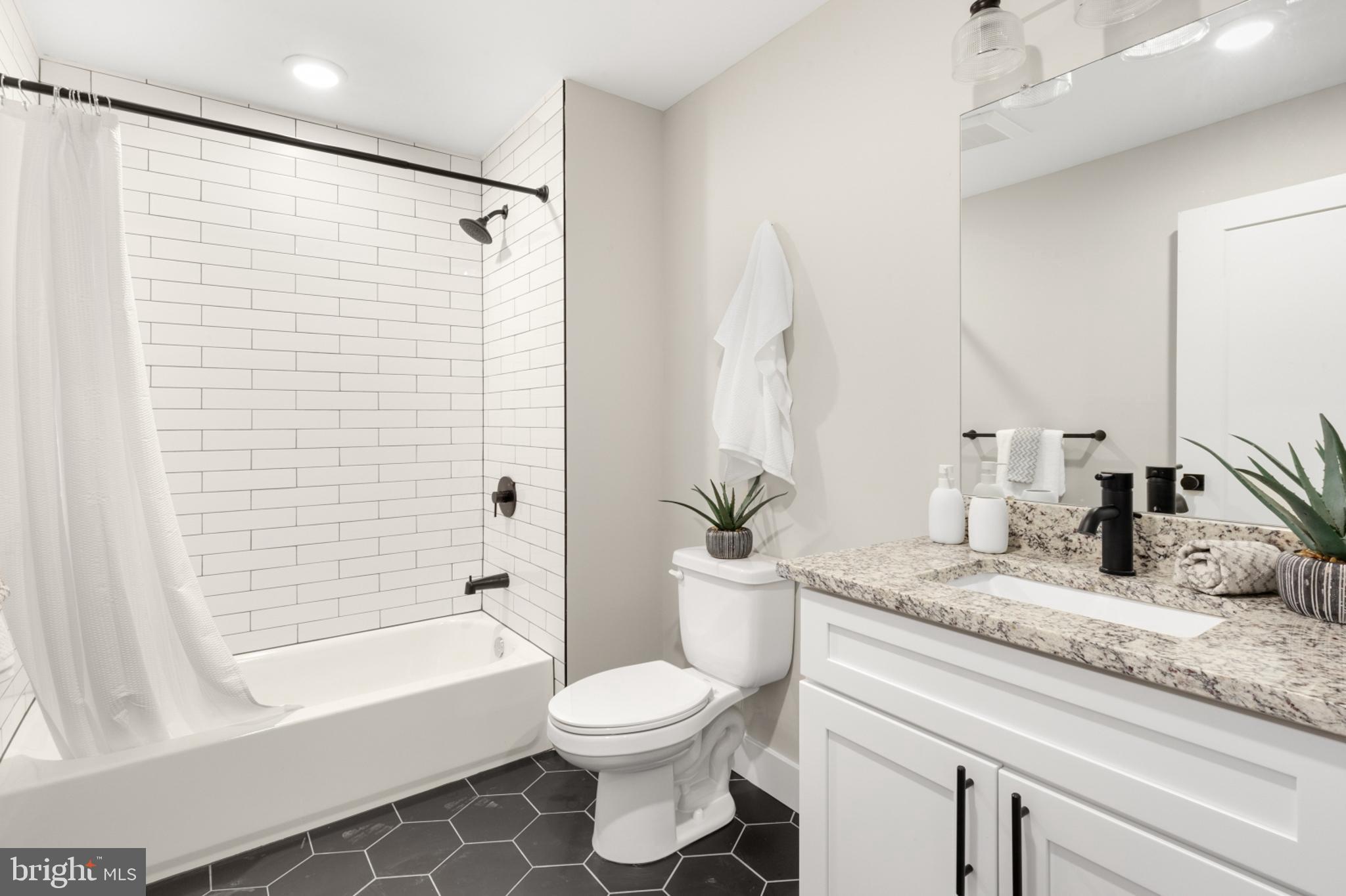 1924 North Front Street, Unit 206 Philadelphia, PA 19122 - Photo 16 of 30 a bathroom with a granite countertop sink toilet a mirror a bathtub and shower