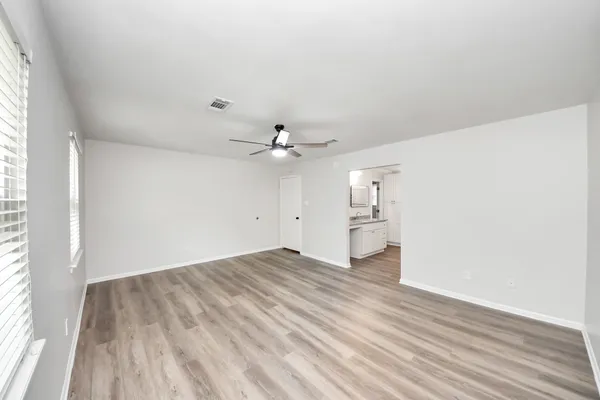 a view of empty room with wooden floor and fan