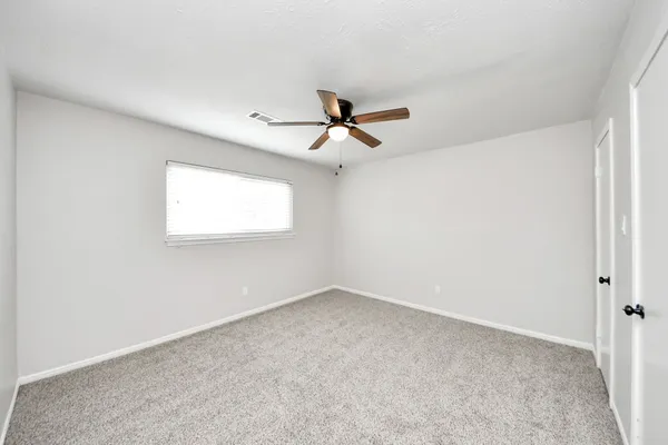an empty room with a window and a ceiling fan