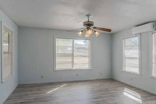 a view of an empty room with window and wooden floor