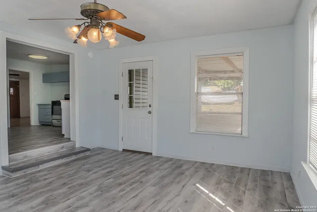 an empty room with wooden floor closet and windows