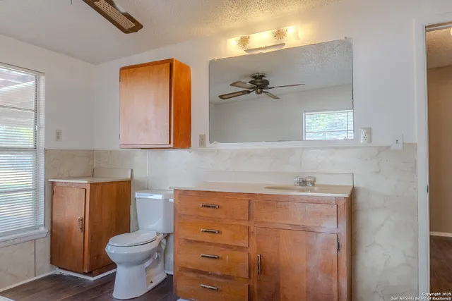 a bathroom with a toilet sink vanity and mirror