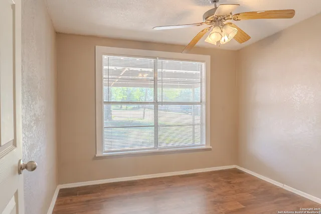 a view of an empty room with a window and wooden floor