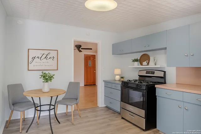 a kitchen with stainless steel appliances a stove a sink cabinets and a dining table