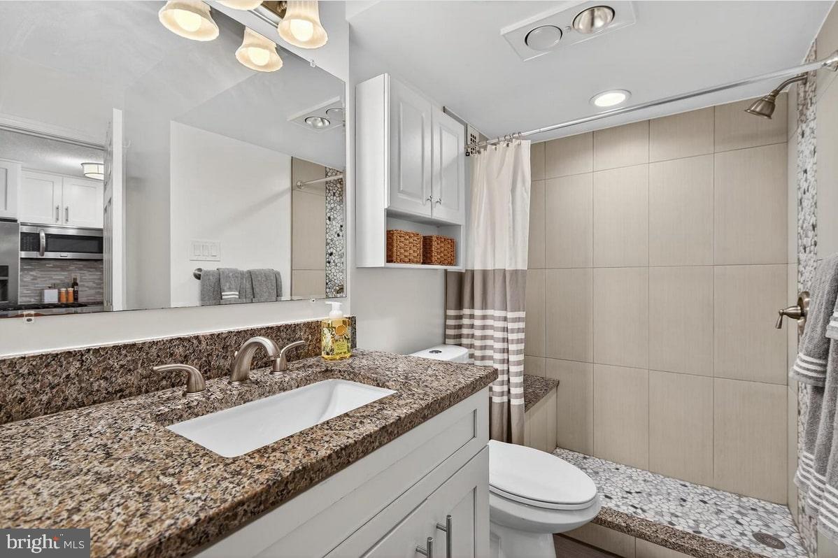 2201 L Street Northwest, Unit 316 Washington, DC 20037 - Photo 16 of 20 a bathroom with a granite countertop sink a mirror a toilet and shower