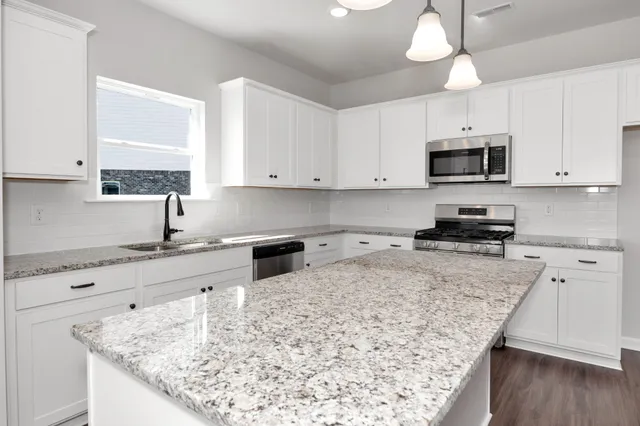 a kitchen with stainless steel appliances granite countertop a sink a stove and microwave with wooden floor