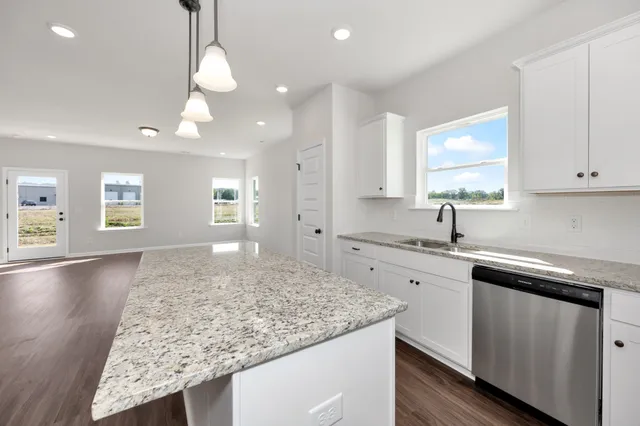 a kitchen with kitchen island granite countertop white cabinets and window