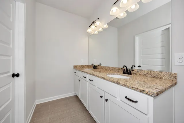 a bathroom with a granite countertop sink a light fixture and a mirror