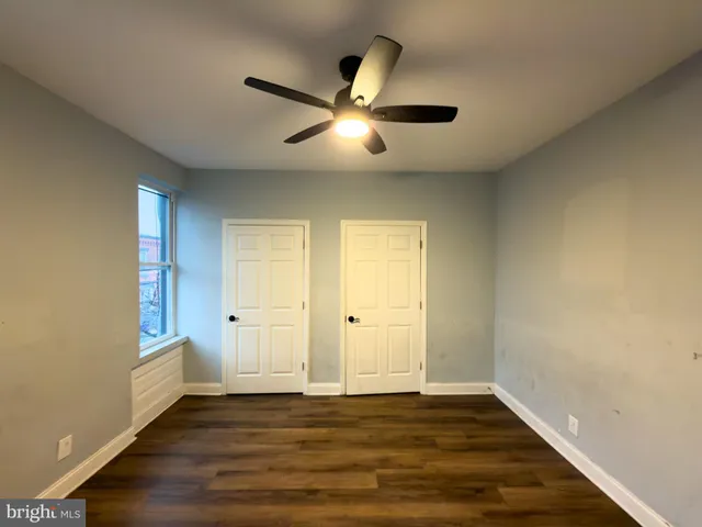 an empty room with wooden floor and ceiling fan