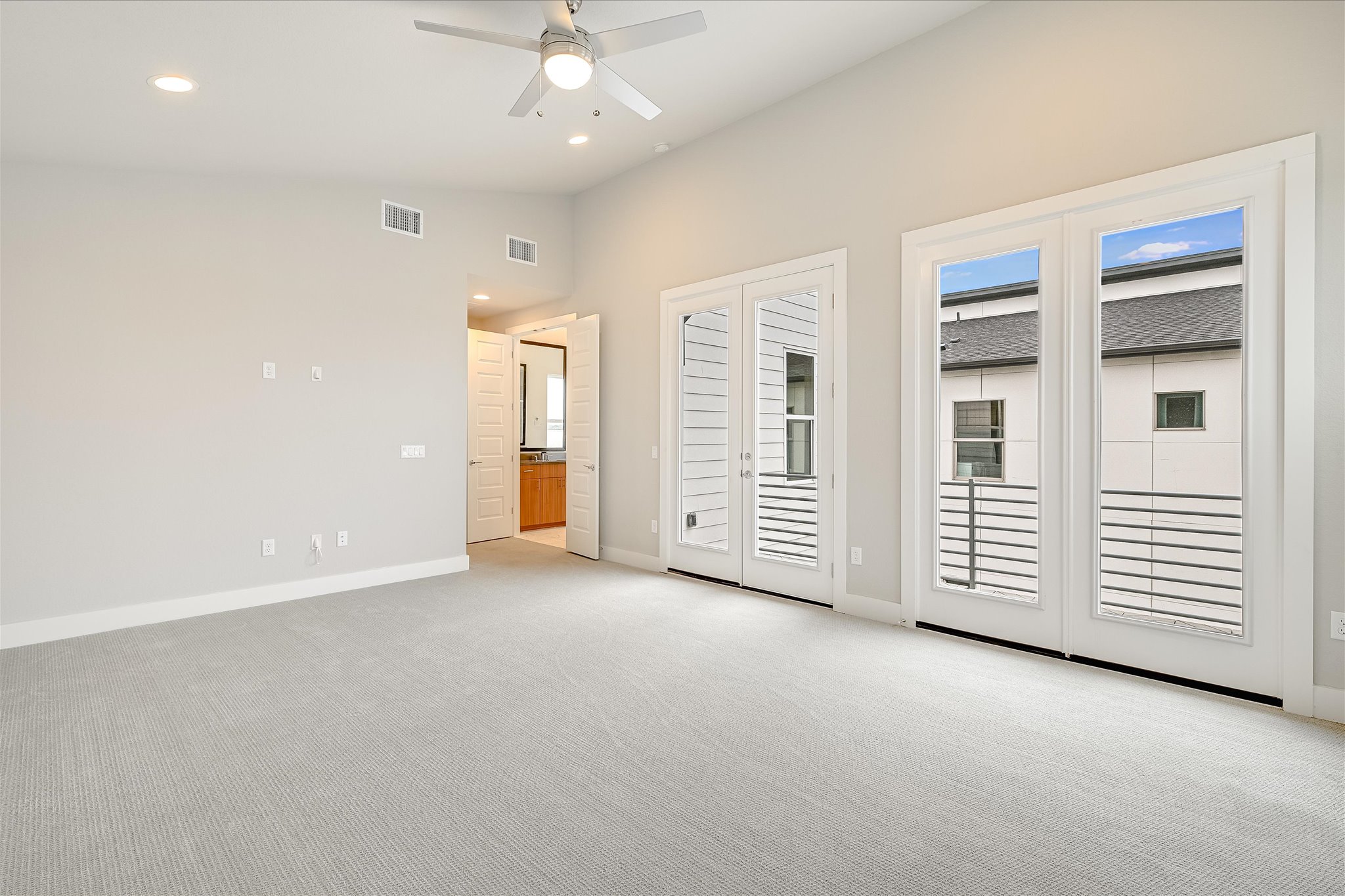 6136 Florencia Lane Austin, TX 78724 - Photo 11 of 40 Primary bedroom with light colored carpet, access to outside, a ceiling fan, vaulted ceiling, and recessed lighting