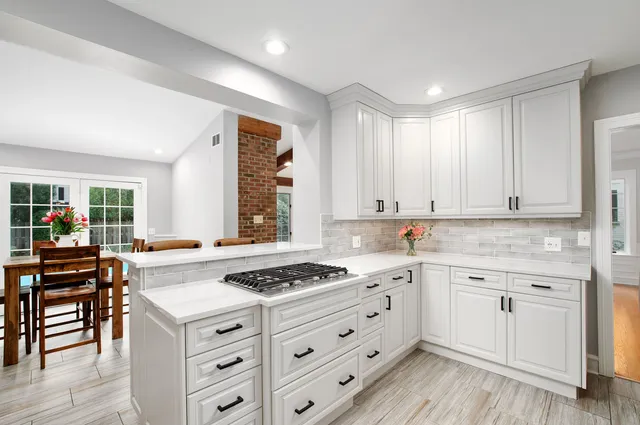 a kitchen with granite countertop a stove a sink dishwasher and white cabinets with wooden floor