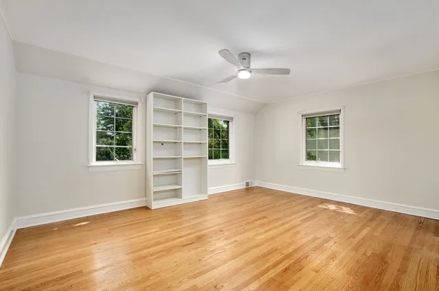 a view of an empty room with a window and wooden floor