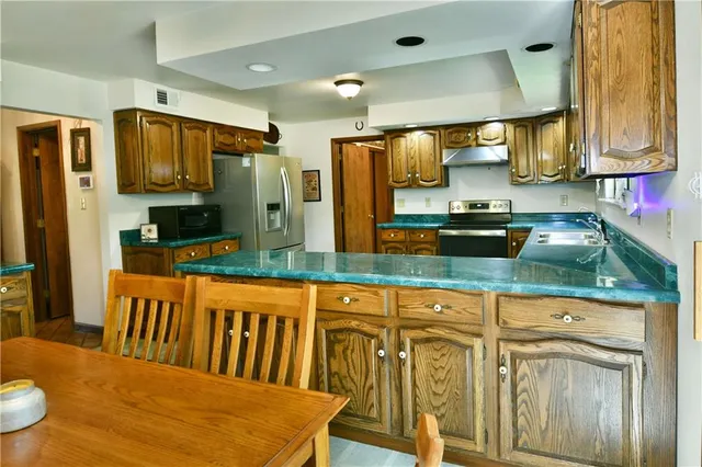 a kitchen with stainless steel appliances granite countertop a kitchen island a stove a sink cabinets and a dining table