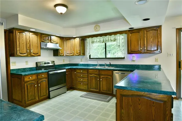 a kitchen with granite countertop a stove a sink dishwasher and cabinets with wooden floor