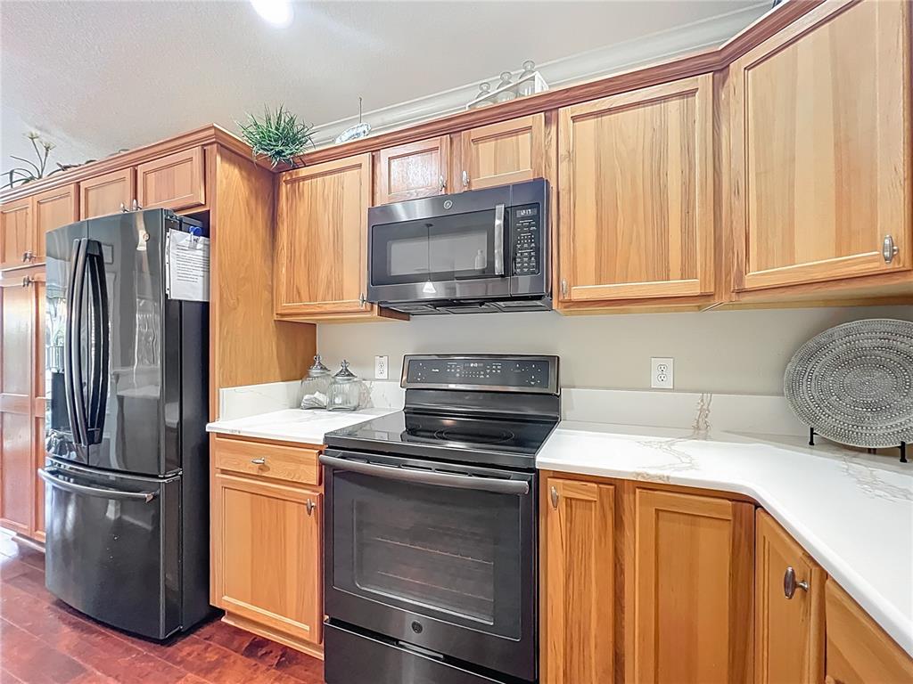 2875 Rain Lily Loop The Villages, FL 32163 - Photo 12 of 36 a kitchen with granite countertop a refrigerator stove and microwave