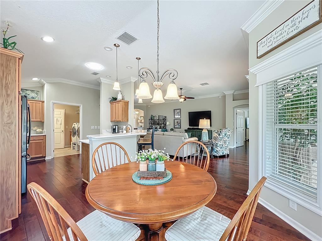 2875 Rain Lily Loop The Villages, FL 32163 - Photo 13 of 36 a dining room with wooden floor a chandelier a wooden table and chairs