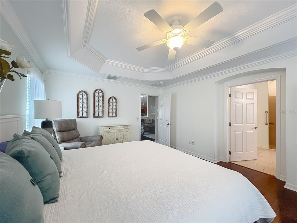 2875 Rain Lily Loop The Villages, FL 32163 - Photo 22 of 36 a spacious bedroom with a bed and a chandelier