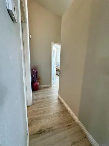 a view of a hallway with wooden floor and a bathroom