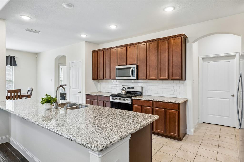 11732 Wulstone Road Fort Worth, TX 76052 - Photo 6 of 34 Kitchen featuring granite countertops, wood-finish cabinetry, stainless steel appliances, a subway tile backsplash, and recessed lighting