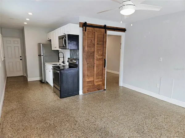 a view of a kitchen with a sink refrigerator cabinets and a window