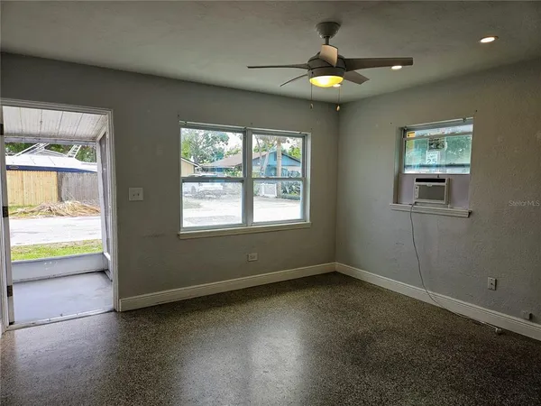 an empty room with ceiling fan and window