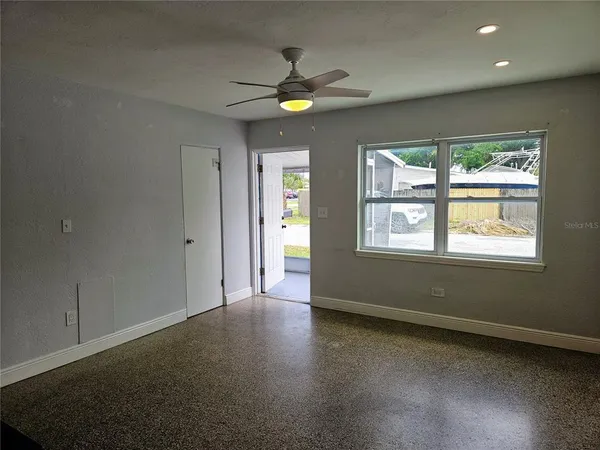 an empty room with windows and chandelier fan