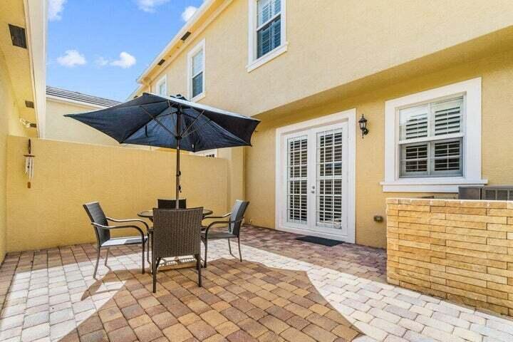 207 Edenberry Avenue Jupiter, FL 33458 - Photo 10 of 16 a patio with a table and chairs under an umbrella