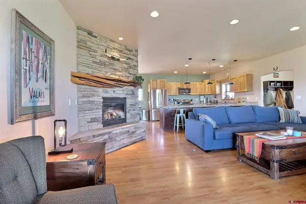 a kitchen with stainless steel appliances granite countertop a refrigerator a sink dishwasher a dining table and chairs with wooden floor