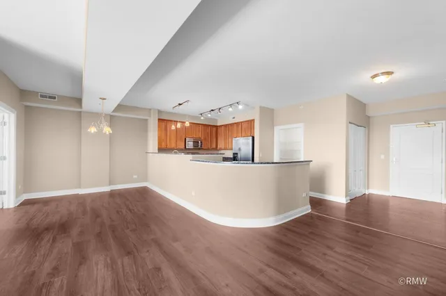 a view of a big room with wooden floor and windows