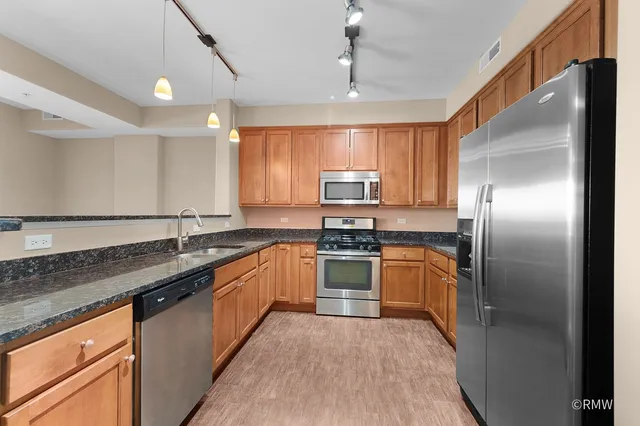 a kitchen with stainless steel appliances granite countertop a sink a stove a refrigerator cabinets and a counter top space