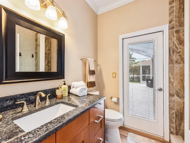 a bathroom with a granite countertop sink a toilet and a mirror