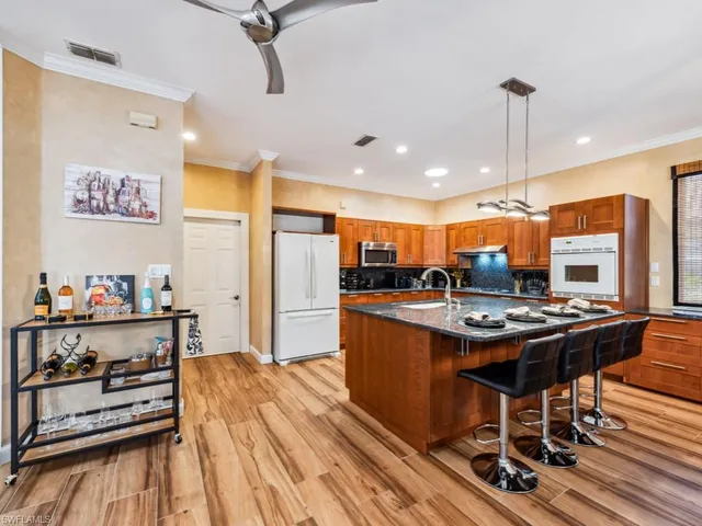 a kitchen with stainless steel appliances a stove a refrigerator and countertop dining table with wooden floor