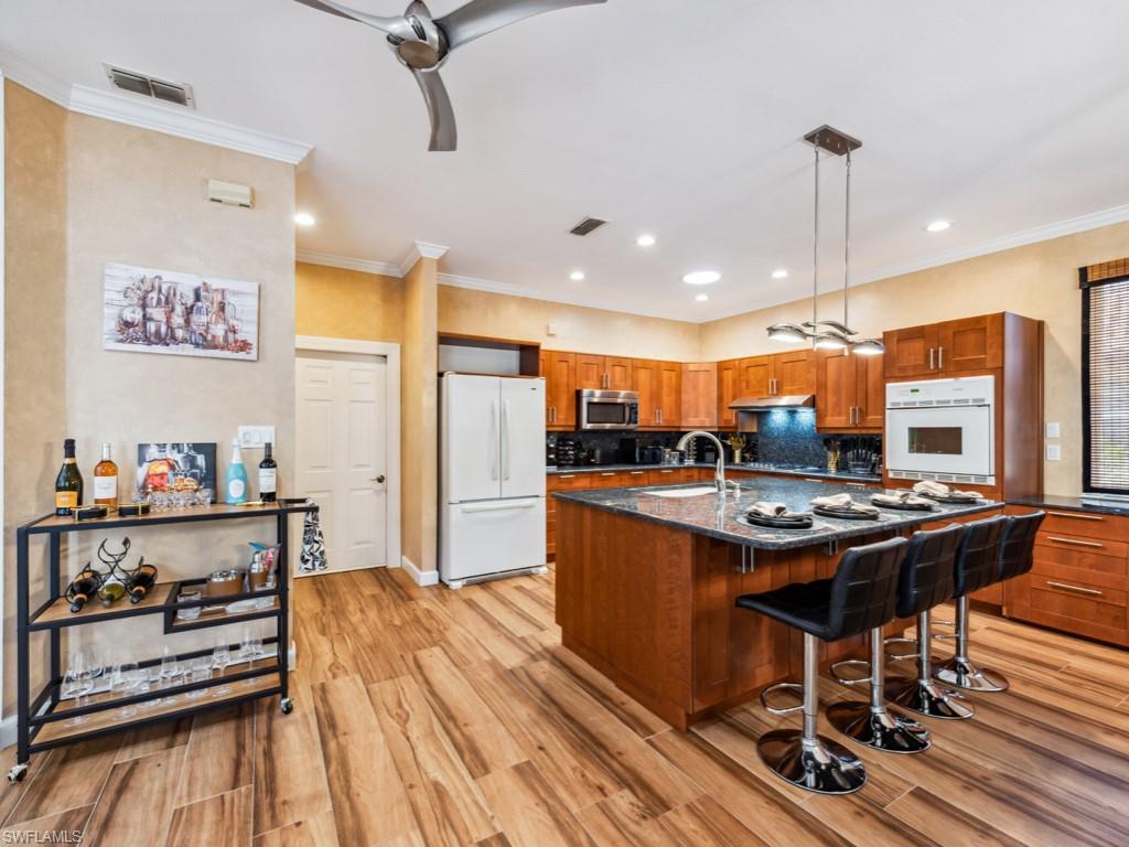 127 Palmetto Dunes Circle Naples, FL 34113 - Photo 7 of 20 a kitchen with stainless steel appliances a stove a refrigerator and countertop dining table with wooden floor
