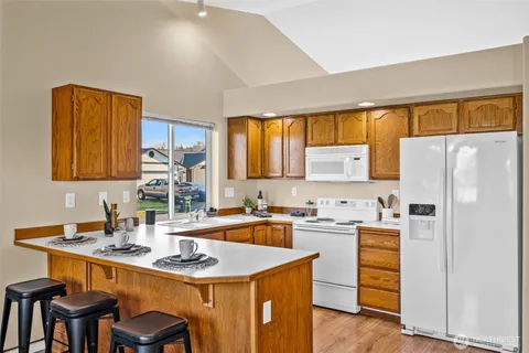 a kitchen with refrigerator a sink a stove and chairs