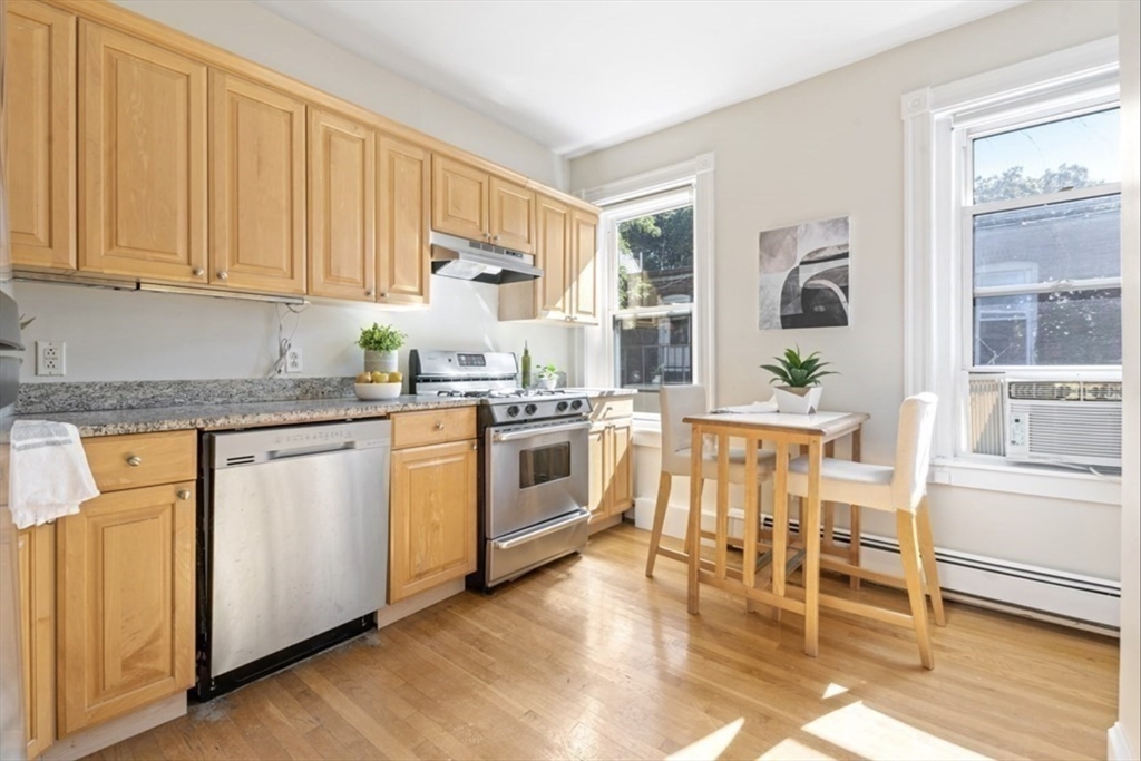 120 Brook Street, Unit 3 Brookline, MA 02445 - Photo 3 of 10 a kitchen with a stove a sink and white cabinets with wooden floor