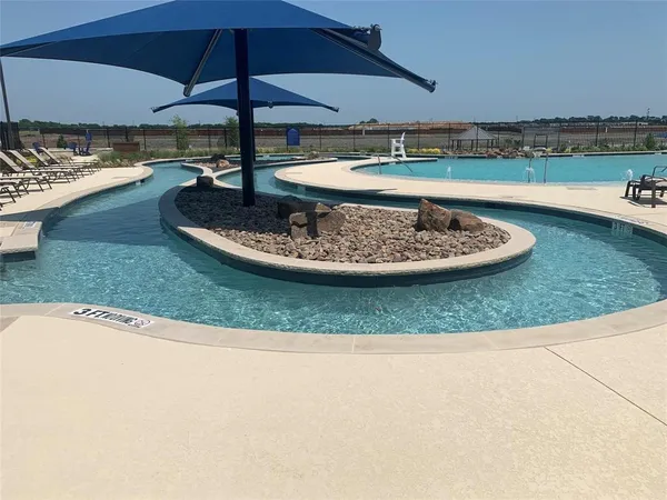 a view of a swimming pool with a table and chairs under an umbrella