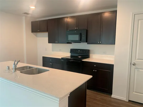 a kitchen with a sink a microwave and cabinets