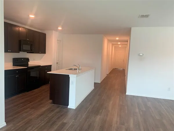 a large kitchen with stainless steel appliances a large counter top a stove a sink and a refrigerator