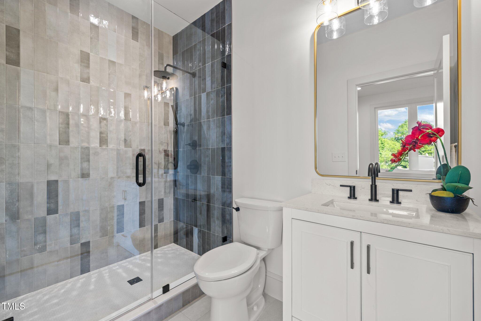 805 Tower Street, Unit 102 Raleigh, NC 27607 - Photo 25 of 36 a bathroom with a shower sink vanity mirror and toilet