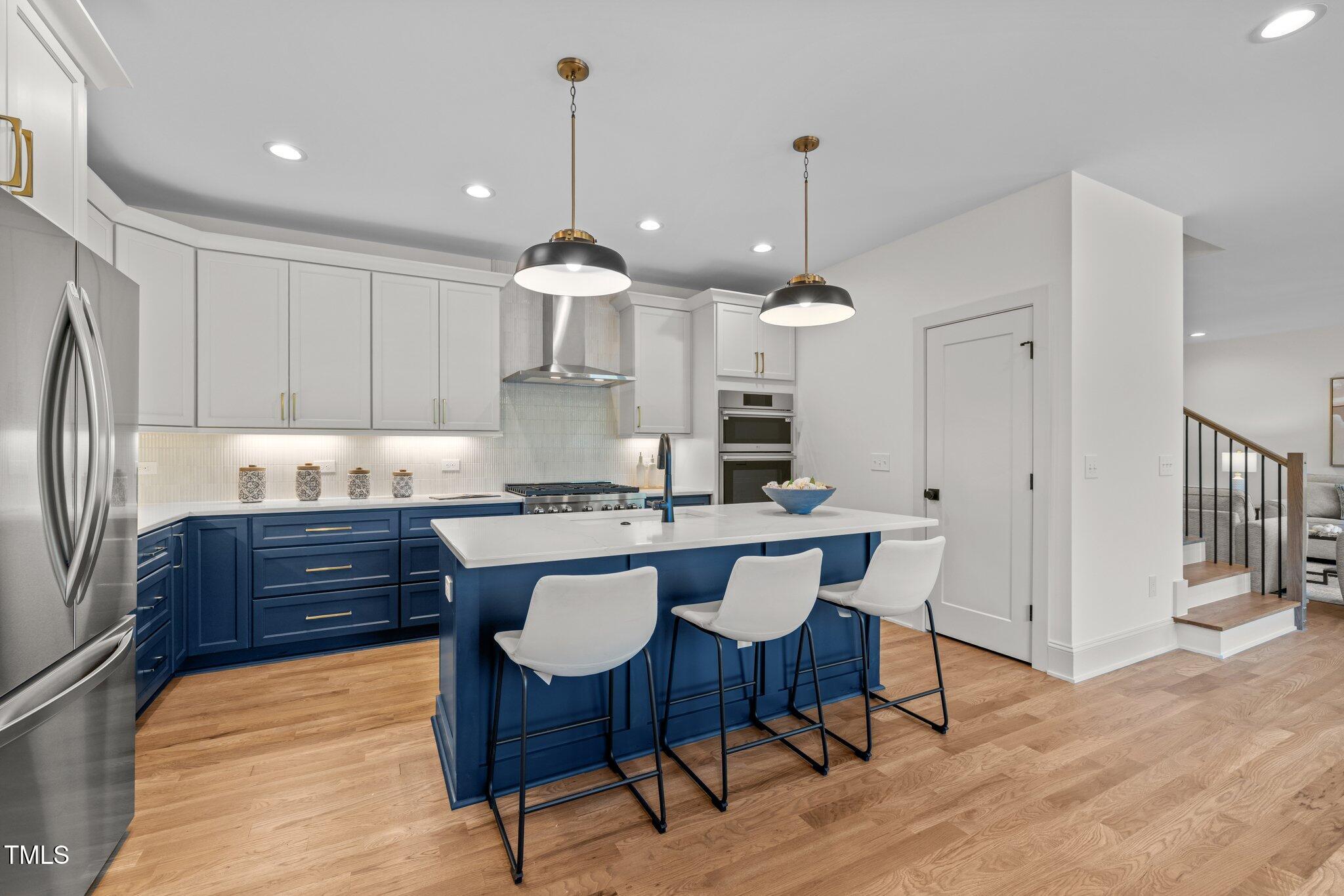 805 Tower Street, Unit 102 Raleigh, NC 27607 - Photo 7 of 36 a kitchen with stainless steel appliances granite countertop a sink a stove a refrigerator and island with wooden floor